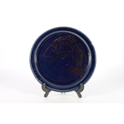 25 - Studio pottery plate with gold fish decoration on a midnight blue ground, 28cm diameter.