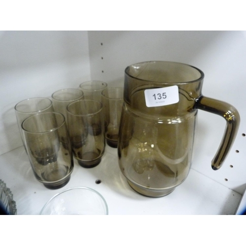 135 - Smokey glass lemonade set, other glassware etc (one shelf).