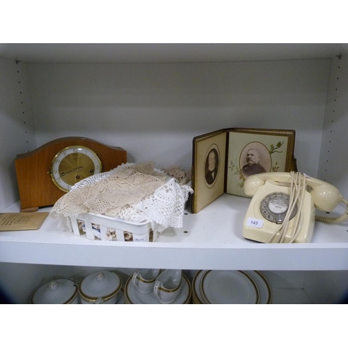 143 - Victorian photograph album, cream telephone, mantel clock and various table linen (one shelf).