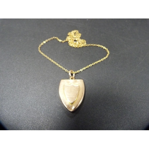 258 - 15ct gold shield-shaped locket, 13.1g, on yellow metal chain attachment.