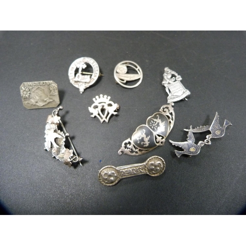 263 - Collection of silver and white metal badges and brooches to include a cameo brooch, clan brooch, Luc... 