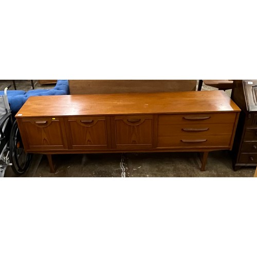 601 - Teak three door sideboard; with three drawers raised on shaped supports