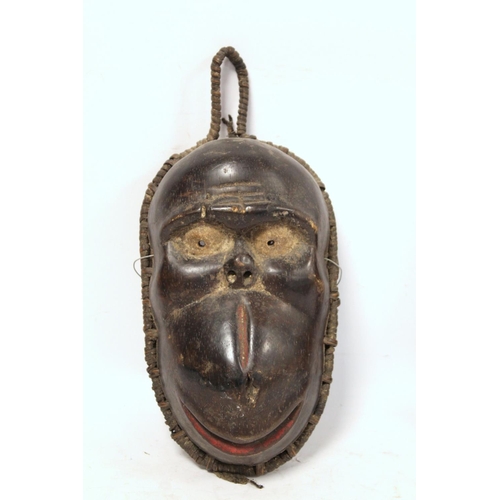 366 - African carved hardwood monkey mask decorated with white and red pigments, with cane binding and fri... 