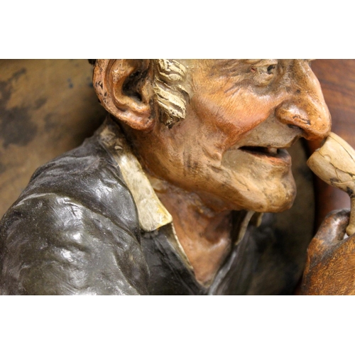 380 - Pair of Continental pottery and treen wall plaques, depicting an elderly man with a pipe and a woman... 