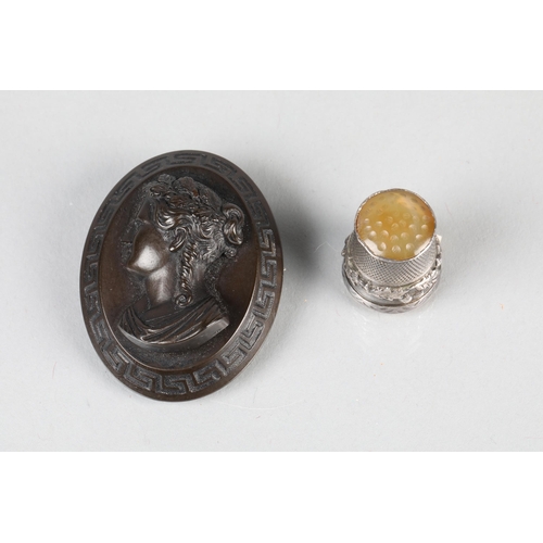 84 - Bakelite brooch with classical maiden bust within Greek border; together with a silver thimble (2)