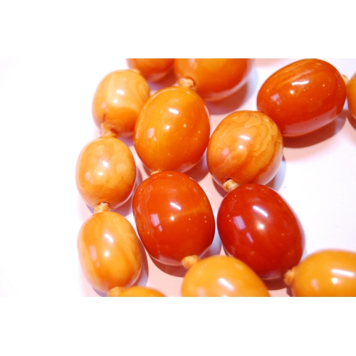 75 - Amber necklace of ovoid beads, 153g.