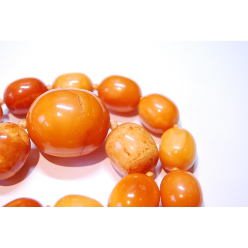 75 - Amber necklace of ovoid beads, 153g.