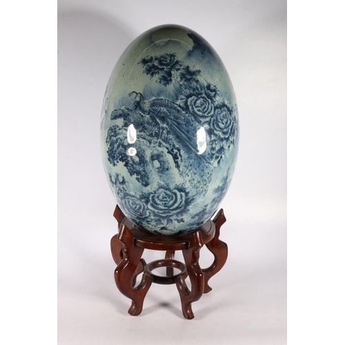 125A - Large oriental ceramic egg on stand decorated with birds of paradise.