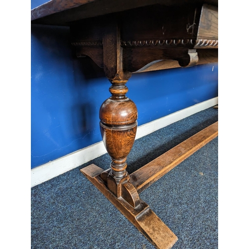 475 - An oak refectory table with egg and dart detail to the apron on cup and cover supports and trestle b... 