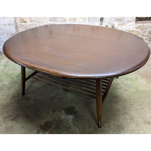 483 - Ercol dark elm top oval coffee table with turned supports united by spindle lower tier, 44cm high x ... 