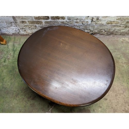 483 - Ercol dark elm top oval coffee table with turned supports united by spindle lower tier, 44cm high x ... 