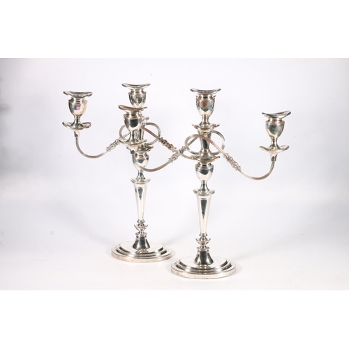 72 - Pair of silver plated copper two branch, three light candelabra raises on stepped oval bases, 46cm t... 