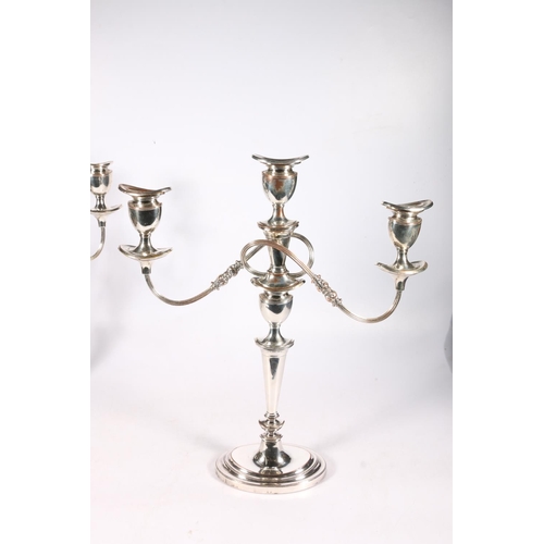 72 - Pair of silver plated copper two branch, three light candelabra raises on stepped oval bases, 46cm t... 