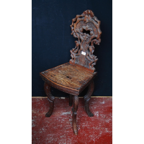 417 - Black Forest carved oak hall chair, the naturalistic back rest applied with flowerheads and leaves, ... 