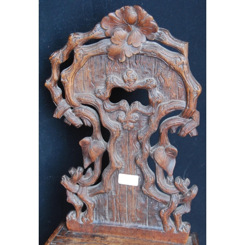 417 - Black Forest carved oak hall chair, the naturalistic back rest applied with flowerheads and leaves, ... 