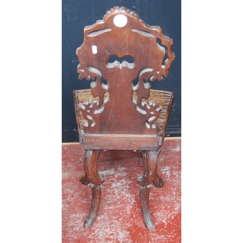 417 - Black Forest carved oak hall chair, the naturalistic back rest applied with flowerheads and leaves, ... 