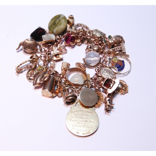 133 - 9ct gold charm bracelet with multiple charms and gems dependant to include a medal, ring, fob, penda... 