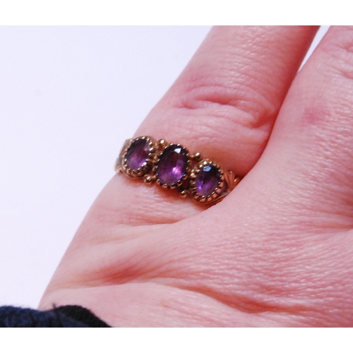 145 - 9ct gold amethyst three-stone ring set with three graduated amethysts, stamped '375', size P, 2g gro... 