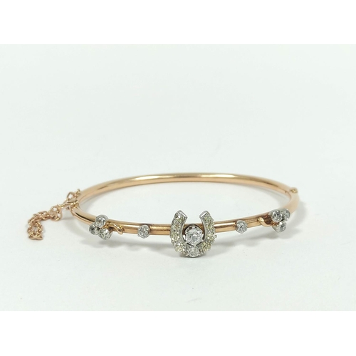 54 - Edwardian gold hinged tubular bangle with diamond set horseshoe and collets '15ct'