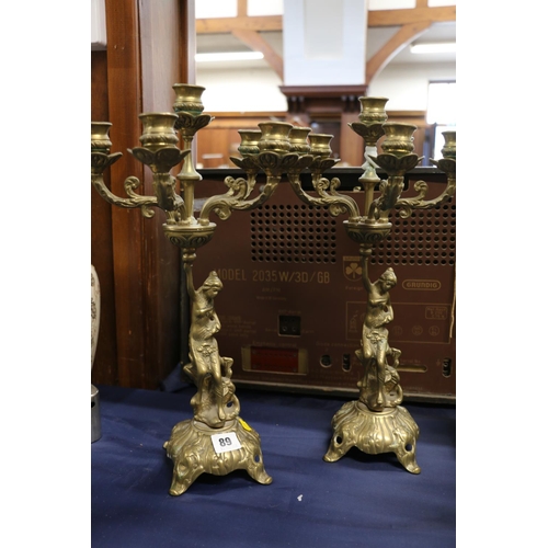 89 - Pair of brass candelabra in the form of seated females holding the candle branches, 43cm.