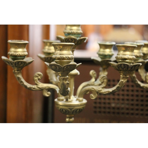 89 - Pair of brass candelabra in the form of seated females holding the candle branches, 43cm.