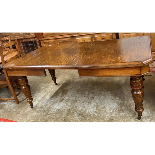 546 - Victorian style oak extending dining table; raised on turned legs terminating in casters (with windi... 