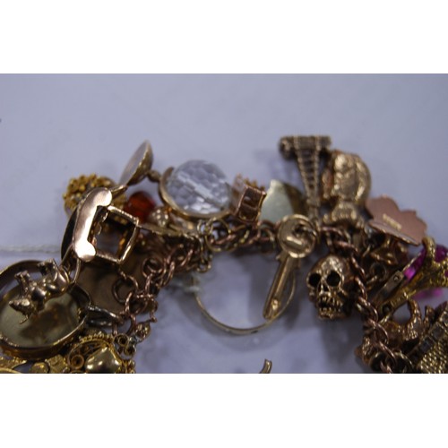 133 - 9ct gold charm bracelet with multiple charms and gems dependant to include a medal, ring, fob, penda... 