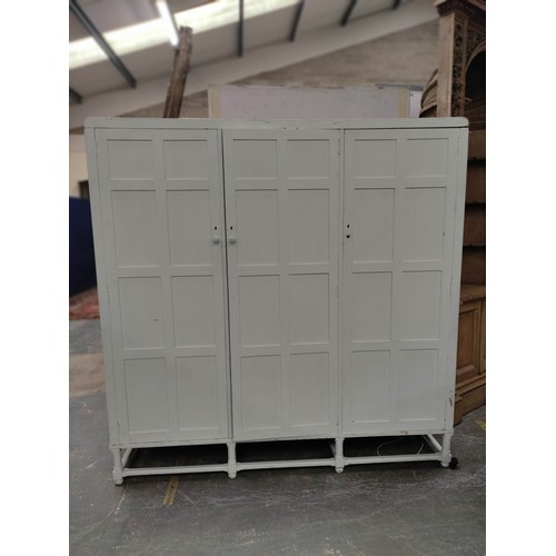 579 - Painted oak triple wardrobe by Heals, the three multi panel doors enclosing drawers, trays and hangi... 