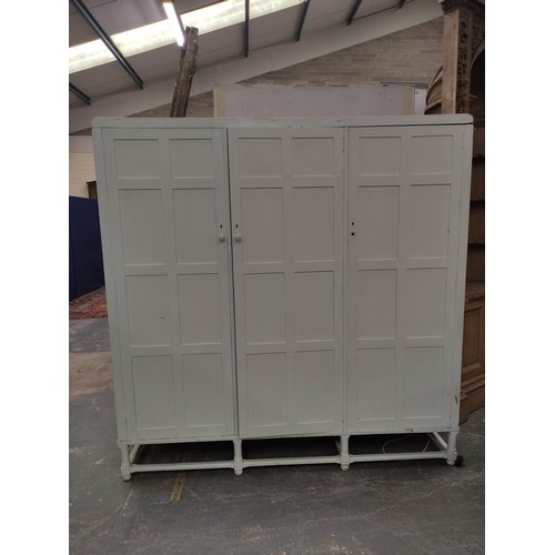 579 - Painted oak triple wardrobe by Heals, the three multi panel doors enclosing drawers, trays and hangi... 