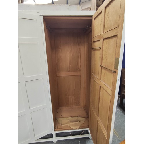 579 - Painted oak triple wardrobe by Heals, the three multi panel doors enclosing drawers, trays and hangi... 