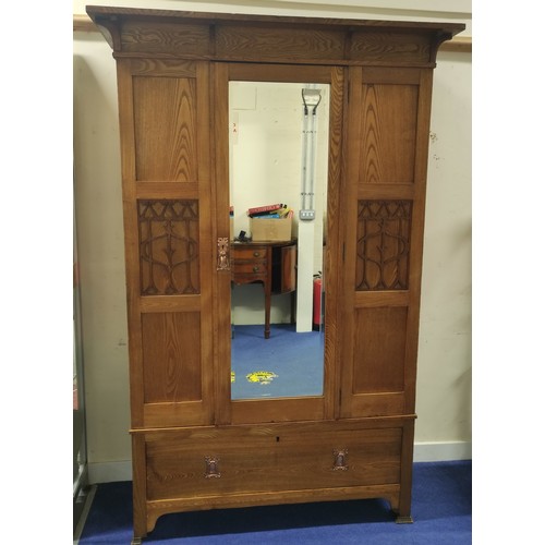 582 - Arts and Crafts wardrobe, probably ash, the mirror door flanked by two fret panels of stylised flowe... 