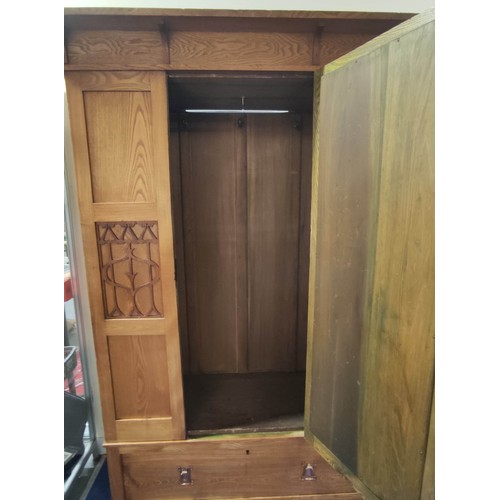 582 - Arts and Crafts wardrobe, probably ash, the mirror door flanked by two fret panels of stylised flowe... 