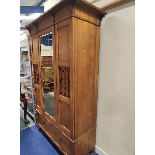 582 - Arts and Crafts wardrobe, probably ash, the mirror door flanked by two fret panels of stylised flowe... 