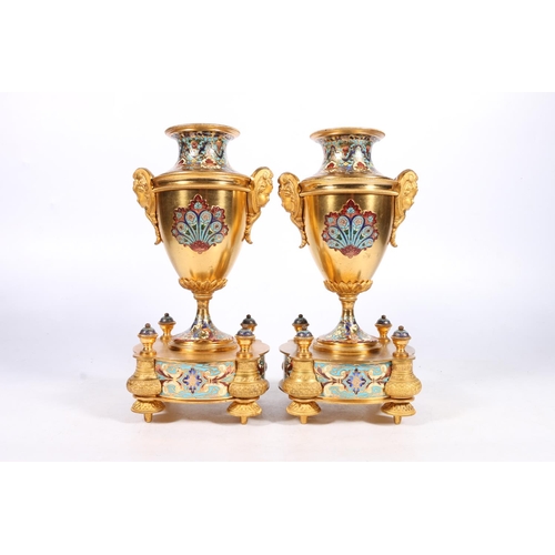 398 - Pair of French gilt metal and enamel clock garniture supporting vases of urn shape with mask handles... 