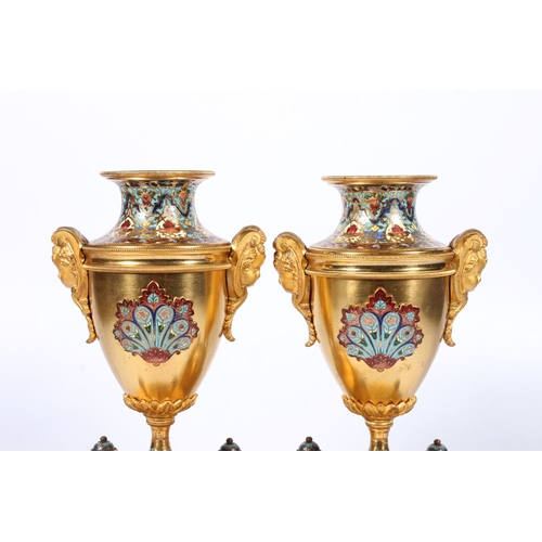 398 - Pair of French gilt metal and enamel clock garniture supporting vases of urn shape with mask handles... 