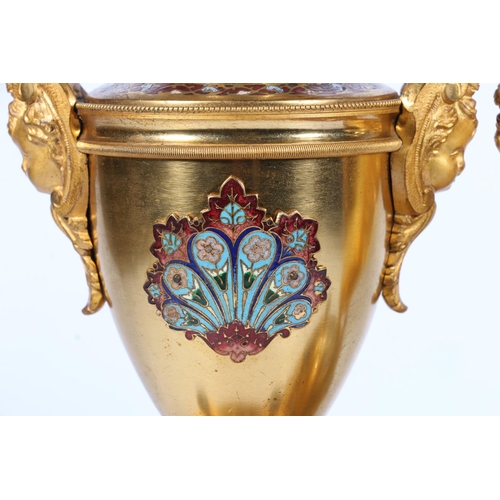 398 - Pair of French gilt metal and enamel clock garniture supporting vases of urn shape with mask handles... 