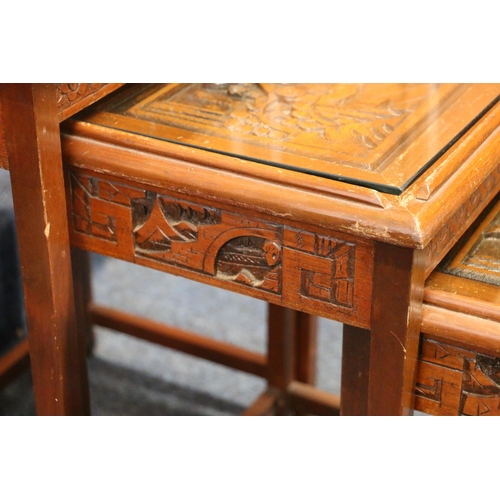 613 - Quatro of Chinese nesting tables, each with a carved top and glass plates, smallest with drawer, lar... 