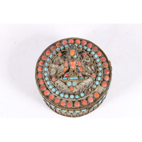 12 - Tibetan metal work box, set with coral and blue stones, decorated with a Buddha, 8cm diameter.