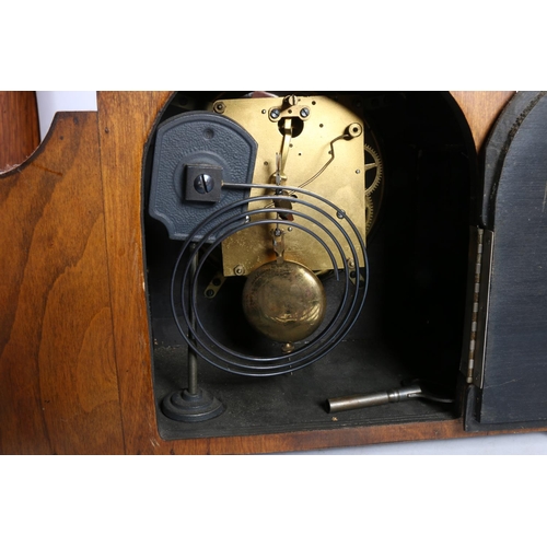 27 - Mahogany and inlaid mantel clock, having shaped sides, raised on shaped supports, 33cm wide.