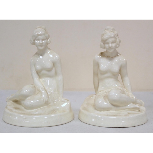 480 - A pair of Royal Worcester white porcelain Art Deco style figures of two seated female nudes on natur... 