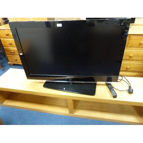 508 - Large Samsung flatscreen television with remote on a contemporary oak-effect television stand.