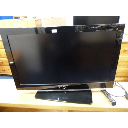 508 - Large Samsung flatscreen television with remote on a contemporary oak-effect television stand.