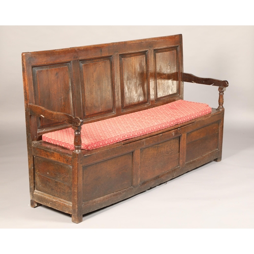 561 - Early 19th century craved oak box settle, with four panel back, flanked with arms, length 175cm, hei... 