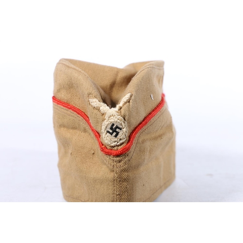 570 - German WWII era summer beret cap with eagle and swastika needlework badge and red piping, the interi... 