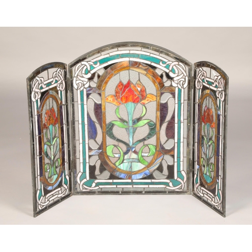 454 - Stained glass triptych folding fire screen, decorated with three stylised panels of flowers, length ... 