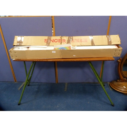 131 - Singer knitting machine, boxed, model KE-1200, on a folding table.