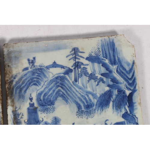 524 - Two 19th century oriental blue and white porcelain tiles, decorated as a mirror image of landscape s... 