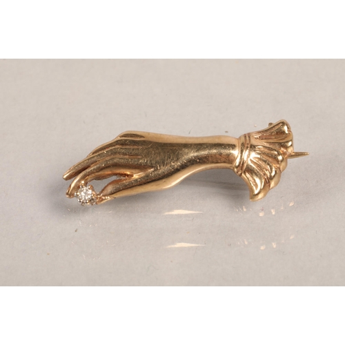 129 - 9ct gold brooch in the form of a hand, set with a small diamond, 3g.