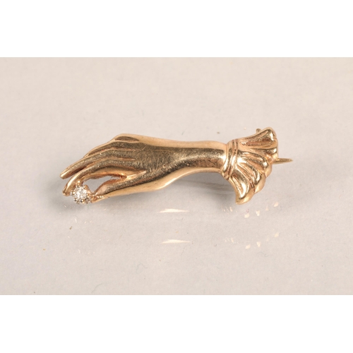 129 - 9ct gold brooch in the form of a hand, set with a small diamond, 3g.