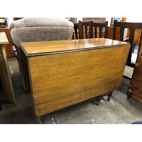 551 - Oak drop-leaf dining room table, a carver and four chairs.  (6)